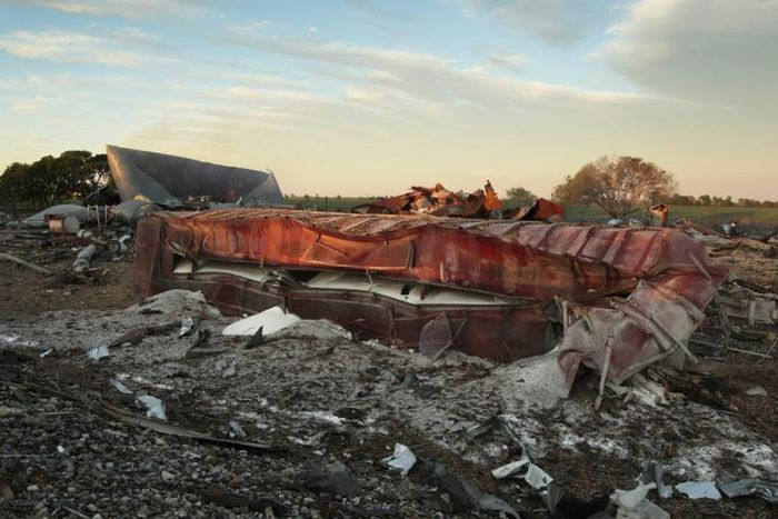 A railroad boxcar filled with ammonium nitrate lays on its side near to the remains of the fertilizer plant that exploded on April 18, 2013 in West, Texas