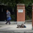 A pedestrian walks past a passed-out drug user on June 25, 2020 in Ottawa, Canada; an emergency government pandemic payment has been used by some addicts to buy drugs, and overdoses have surged
