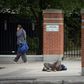 A pedestrian walks past a passed-out drug user on June 25, 2020 in Ottawa, Canada; an emergency government pandemic payment has been used by some addicts to buy drugs, and overdoses have surged