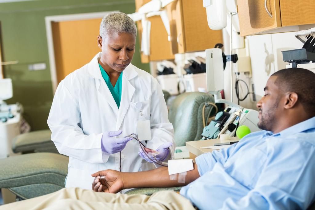 Phlebotomist checking line whle patient donates blood in hospital