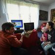 Lucian Cojocaru, a volunteer from "Casa Buna" (The Good Home) NGO, shows a Romanian schoolgirl and her mother how to use a desktop computer, aiding their access to home schooling during the pandemic