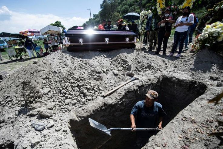 A grave is dug while a family waits during a funeral for a COVID-19 victim at the San Miguel Xico cemetery in Mexico