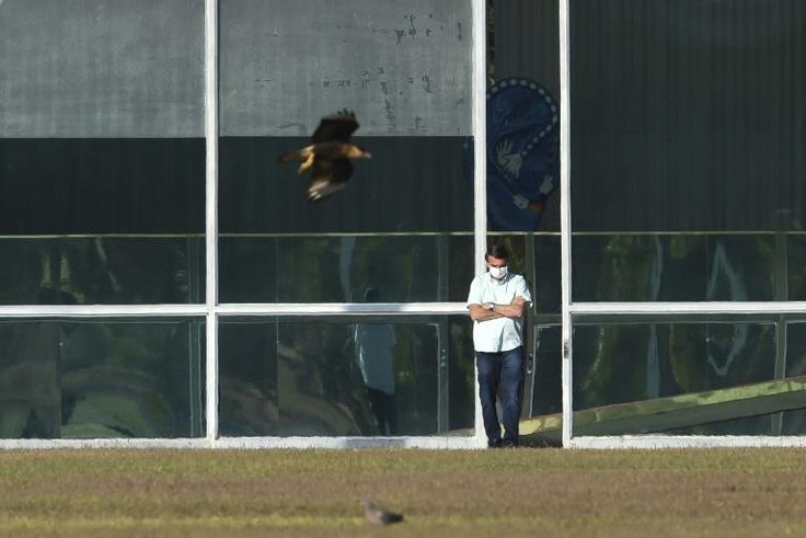 Brazilian President Jair Bolsonaro, standing outside the presidential palace in Brasilia, has tested positive for coronavirus a second time