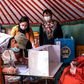 Electoral staff collect the vote of an elderly Mongolian at his home because the man cannot visit a polling station