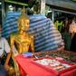 A vendor wearing a face mask against the spread of the coronavirus sits beside a Buddha statue as he waits for customers at an amulet market in Bangkok