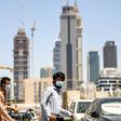 Foreign workers clad in masks to protect against coronavirus push bicycles along a street in the Satwa district of Dubai
