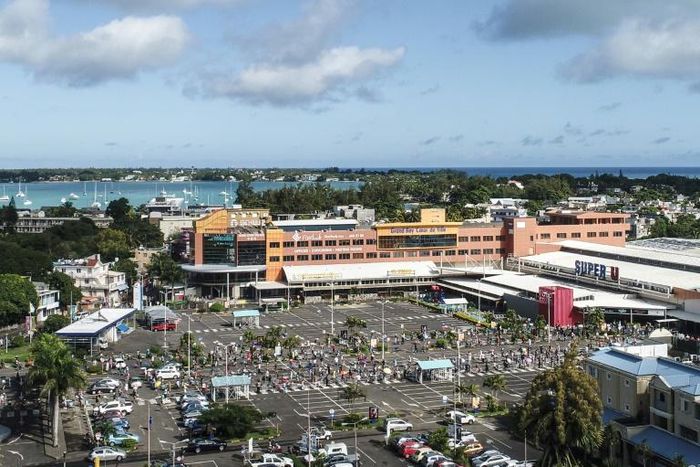 An aerial shot taken in April 2020 shows people waiting while adhering to social distancing in a parking lot before entering a supermarket in Grand Baie, Mauritius; the country has declared wary victory over the coronavirus