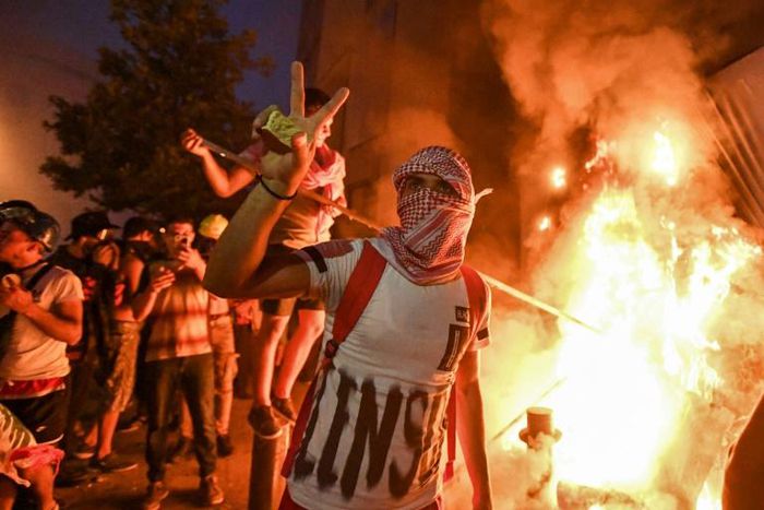 A Lebanese protester flashes the victory sign amid clashes with security forces in the centre of Beirut on Tuesday night