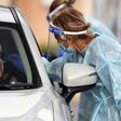 A coronavirus tester takes a swab sample at a drive-through testing station in Melbourne