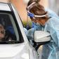 A coronavirus tester takes a swab sample at a drive-through testing station in Melbourne