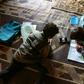 Young pupils follow a lesson on a mobile telephone at a camp for displaced Syrians in the village of Kafr Yahmoul in northwestern Idlib province