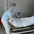Employees lift the body of a COVID-19 victim before loading it into the furnace at the New Sonapur Hindu crematorium in Dubai