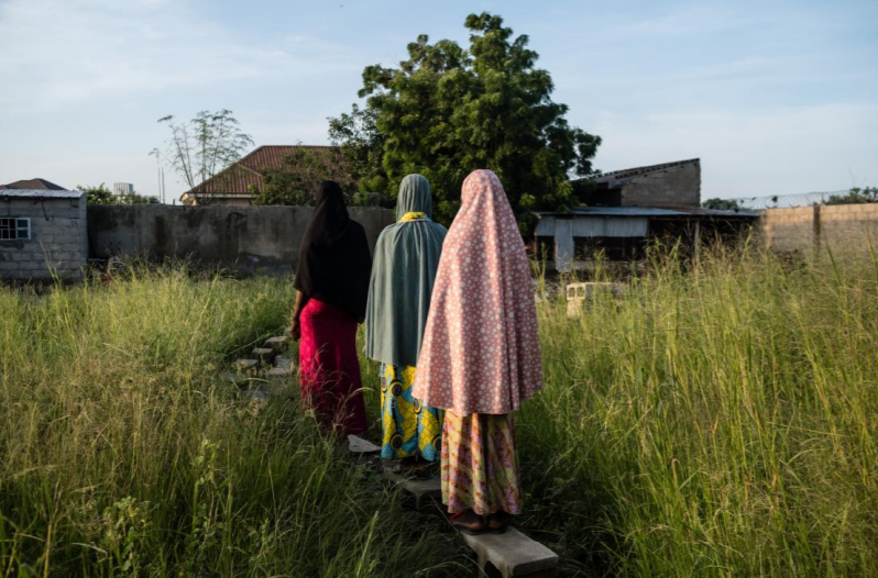 Three women and girls walk home in Maiduguri, Borno, on September 4, 2019. One woman had been abducted by Boko Haram as a girl, and then detained for 15 months by the Nigerian military after escaping. Another spent two years in in detention [Tom Saater...