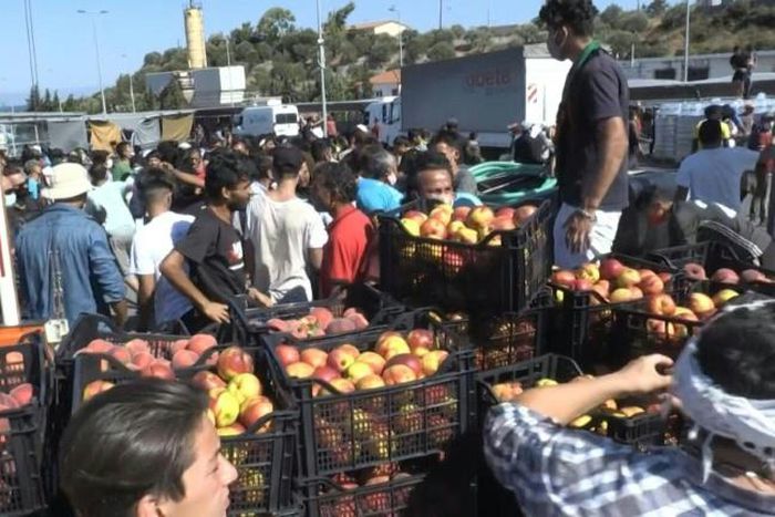 IMAGES Migrants facing homelessness after a fire ravaged Greeece's largest refugee camp rush to get food and water distributed by the governement in a supermarket parking lot where many of them are camped.