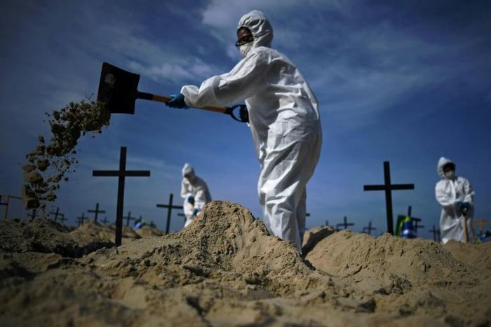 Members of the Rio de Paz NGO dig mock graves on Copacabana Beach on June 11