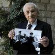 Bach, pictured holding a photograph showing himself (below) during the Eichmann trial, said, 'Not a day passes without me remembering some particular item, or some particular piece of evidence, or some particular moment from the Eichmann trial'
