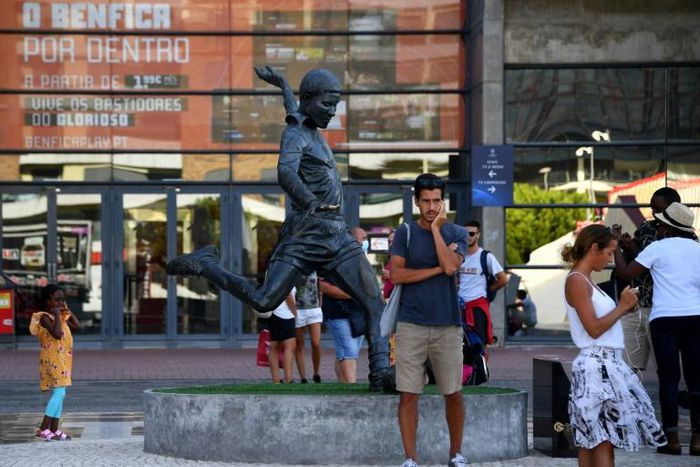 Football fans take pictures next to the statue of Portugal legend Eusebio outside Benfica's Estadio da Luz, which will host the Champions League final on August 23