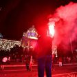 A protestor holds a flare as Serbian police fires tear gas in front of the National Assembly building in Belgrade, on July 7, 2020, to disperse thousands of protesters angry at the return of a weekend coronavirus curfew