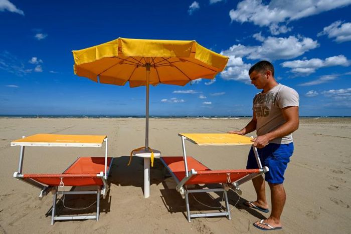 A beach manager spaces out sunbeds on the seafront of Cesenatico on the Adriatic coast