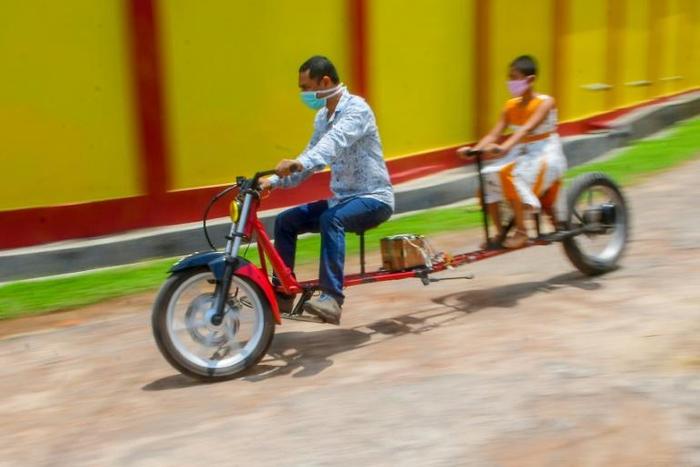 Self-made automobile engineer Partha Saha (L) built a motorbike designed for social distancing