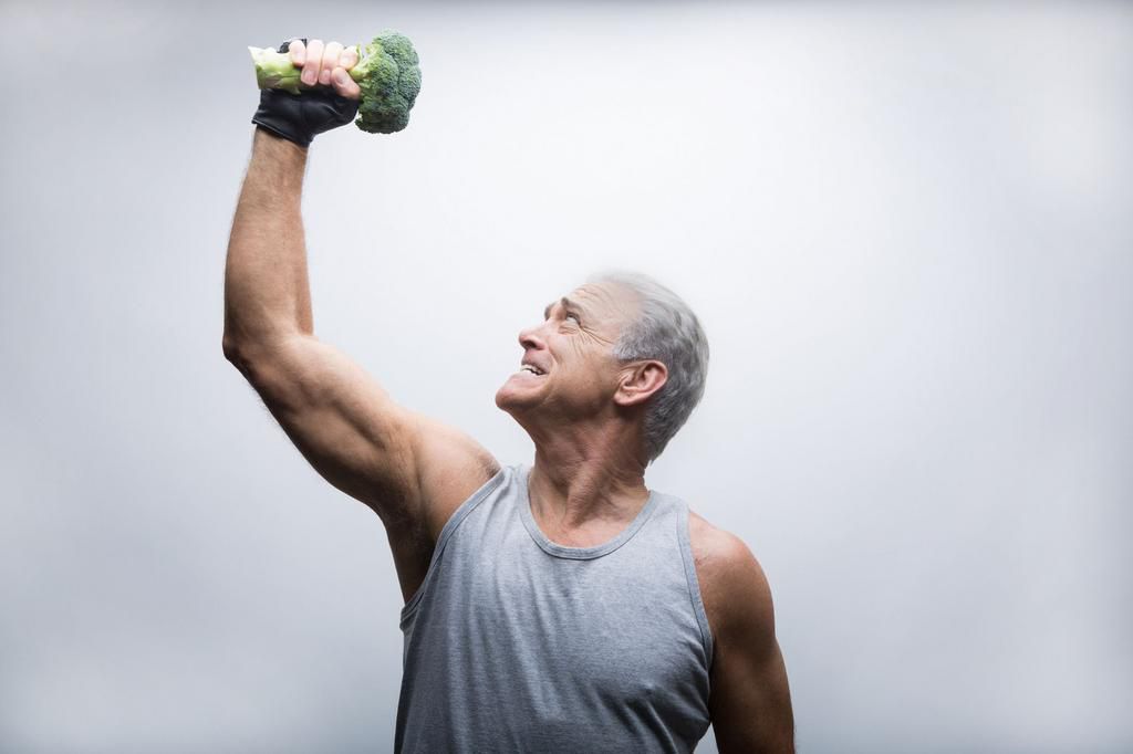 Senior man looking up and lifting broccoli