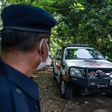 A member of the Royal Malaysia Police stands guard as a forensic vehicle leaves the main entrance of the location where Nora Quoirin's body was found