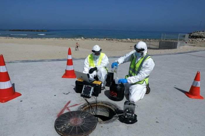 Technicians from Israeli firm Kando extract sewage samples from a manhole near the beach, in the southern coastal Israeli city of Ashkelon