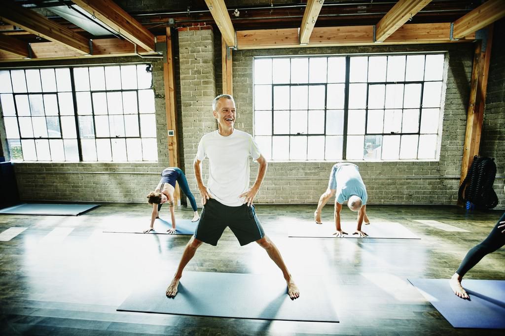 Mature male yoga student laughing during class