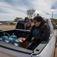 Members of the Larson family who have no running water in their home, collect water from a distribution point in the Navajo Nation town of Thoreau