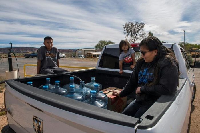 Members of the Larson family who have no running water in their home, collect water from a distribution point in the Navajo Nation town of Thoreau