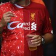 A Liverpool fan wears a half-and-half Liverpool shirt featuring the 1990 (L) and 2020 (R) kits symbolising the 30 years between the club's English league title victories