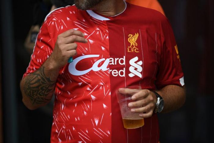 A Liverpool fan wears a half-and-half Liverpool shirt featuring the 1990 (L) and 2020 (R) kits symbolising the 30 years between the club's English league title victories