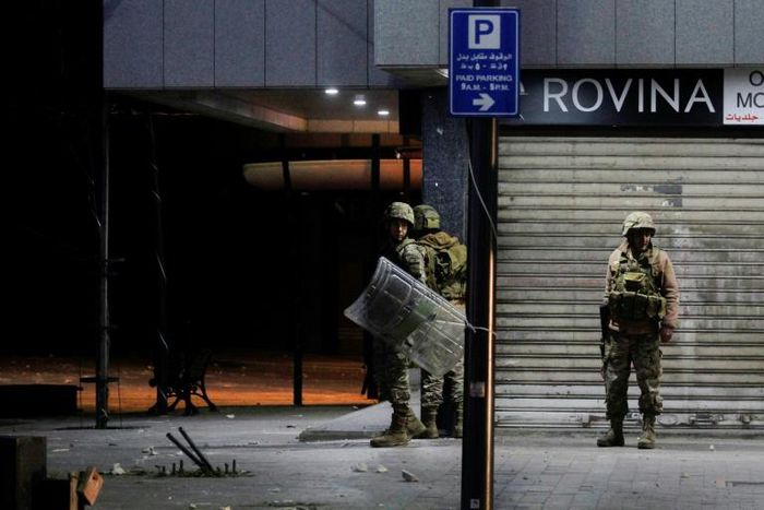 Lebanese troops take cover during overnight confrontations with protesters in the southern city of Sidon as anger over a spiralling economic crisis