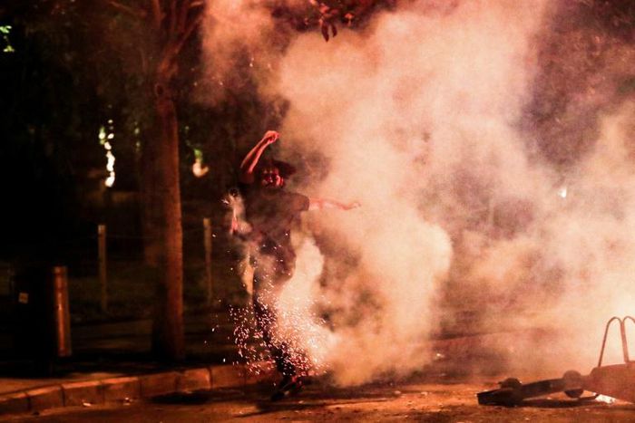 A Lebanese anti-government protester kicks back a tear gas canister fired by security forces during a protest against dire economic conditions in Beirut on Friday night