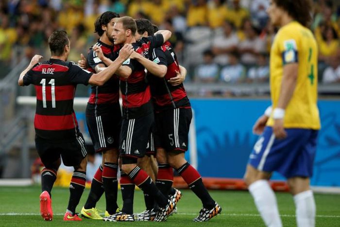 Germany players celebrate after Thomas Mueller opens the scoring against Brazil as a forlorn David Luiz looks on disconsolately