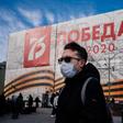 A man wearing a face mask against the spread of the coronavirus walks past a banner for the now much reduced 75th anniversary celebrations in Moscow marking  the victory over Nazi Germany in World War II