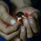 A Pakistani smoker holding a match to a clump of hashish to soften it before mixing it with cigarette tobacco