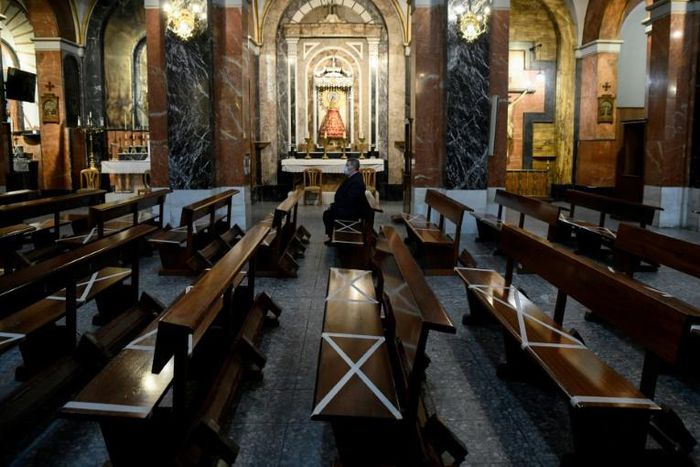A man wearing a face mask sits on pews marked to help people keeping their social distance at Our Lady of Covadonga Parish in Madrid on May 13, 2020 during a national lockdown to prevent the spread of the COVID-19 diasease