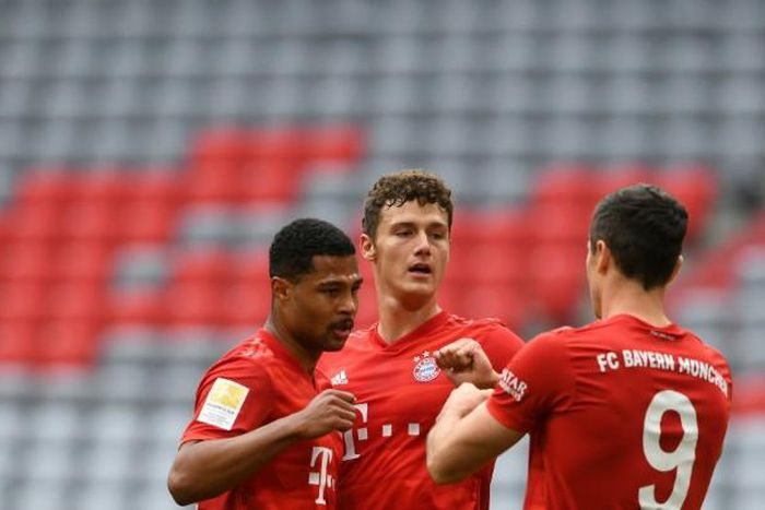 Bayern Munich striker Robert Lewandowski (R) celebrates with defender Benjamin Pavard (C) and winger Serge Gnabry.