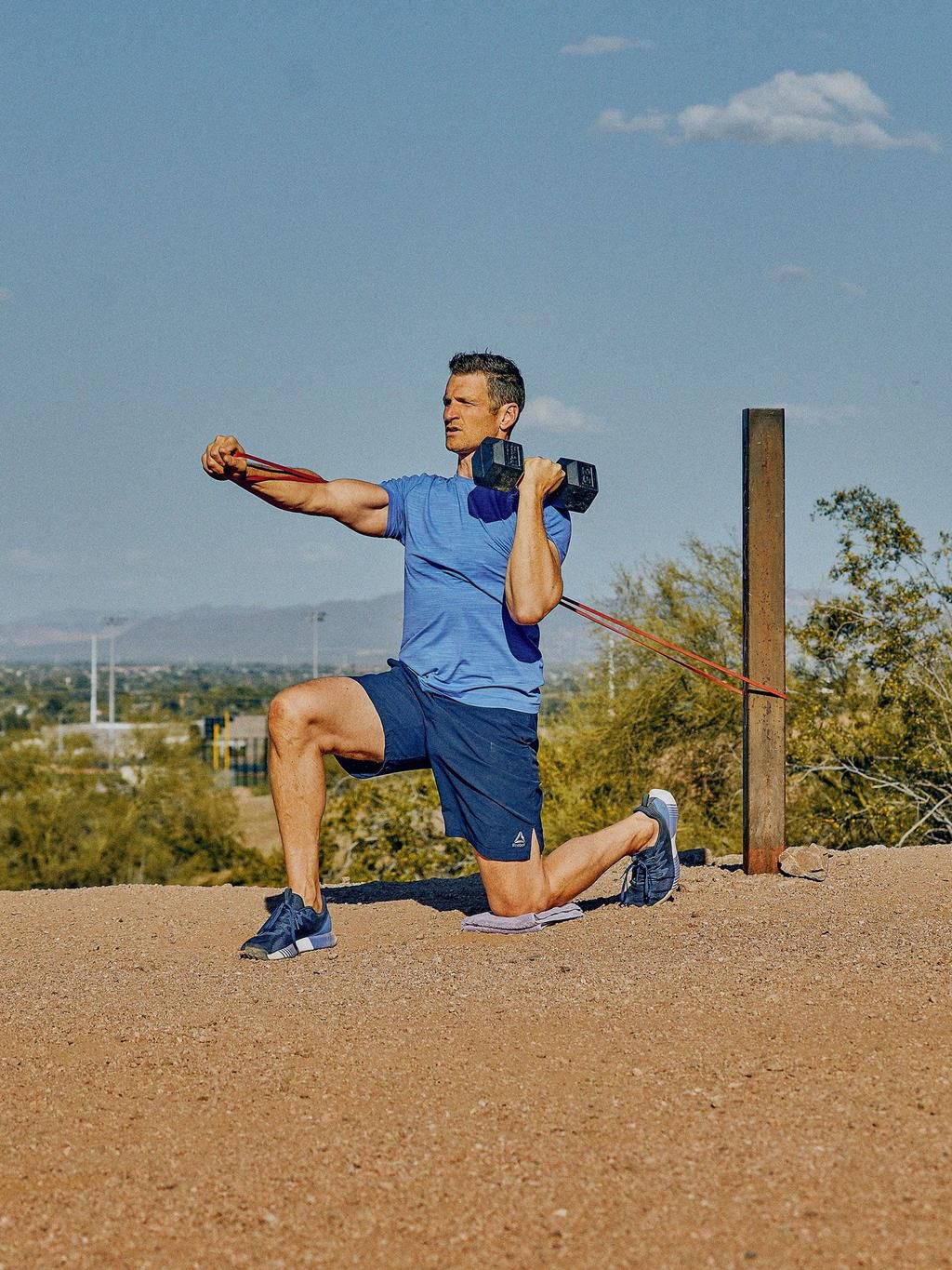 man in half kneeling stance doing a band press from sling subsystems