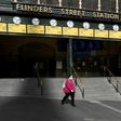 A woman walks out of a near-deserted Flinders Street Station in Melbourne after the state announced new restrictions to contain coronavirus