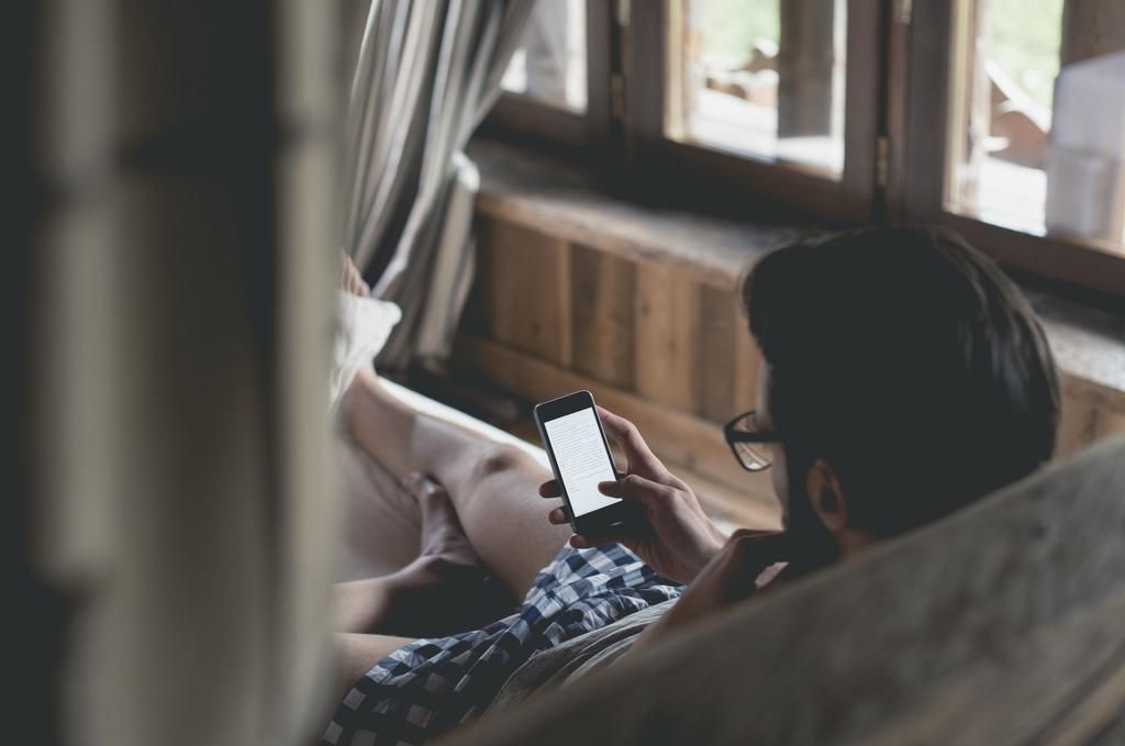 Young man using smartphone lying in bed at home
