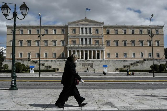 A woman wearing a face mask walks past the empty Syntagma Square in Athens, in front of the Greek Parliament early during the outbreak of COVID-91.
