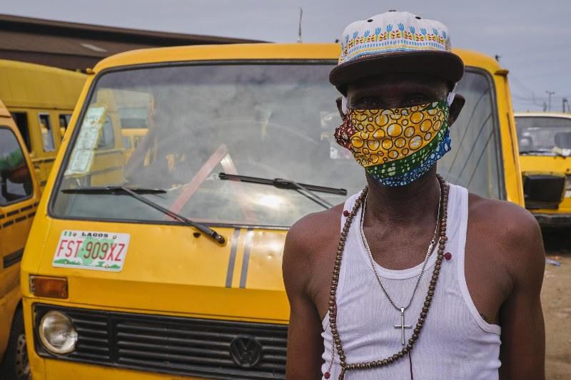 A bus conductor in Lagos complies with the face mask directive the right way (Pulse)