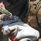 An Afghan security officer carries a newborn baby from a hospital after it is attacked in Kabul