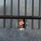 A man watches from behind a closed gate after a raid at the prison in Jalalabad