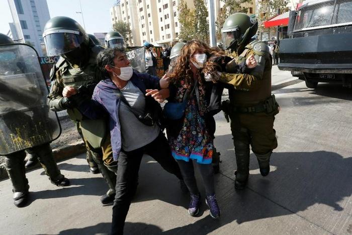 Riot police arrest demostrators in Santiago on Friday after breaking up a May Day protest that contravened social distancing rules