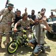 Fighters loyal to Libya's UN-recognised Government of National Accord pose for a picture with a children's bicycle  as they celebrate the capture of the town of Tarhuna, about 65 kilometres southeast of the capital Tripoli