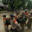 Rescuers carry a body recovered after flash floods in South Sulawesi which killed at least 15 people