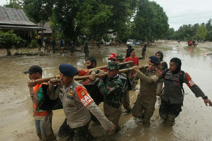 Rescuers carry a body recovered after flash floods in South Sulawesi which killed at least 15 people